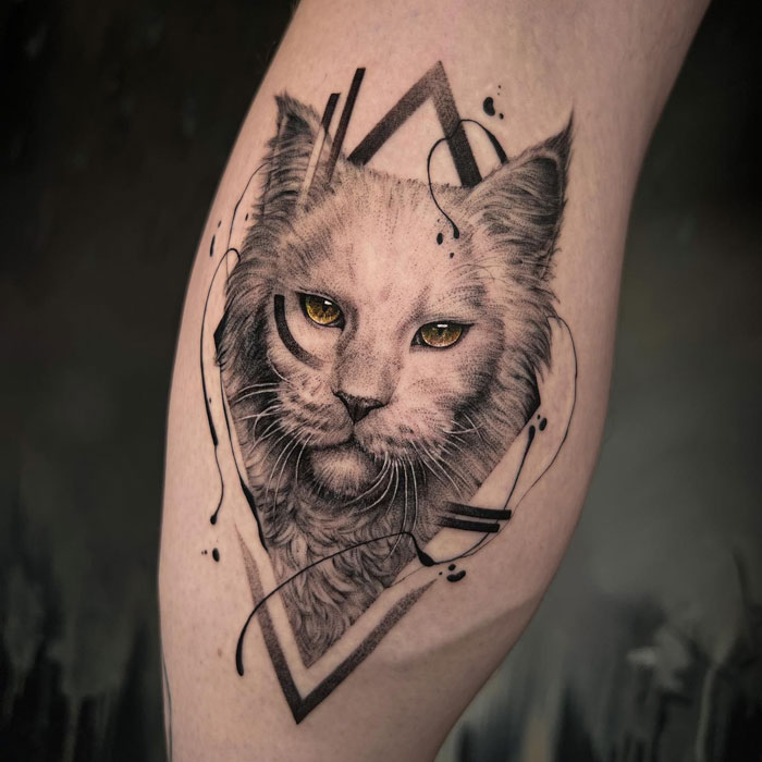 Animal tattoo of a cat's face with artistic geometric elements on a forearm.
