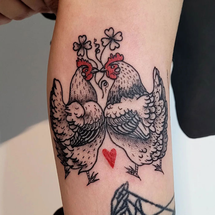 Chicken-themed animal tattoo on arm with clover and heart design.