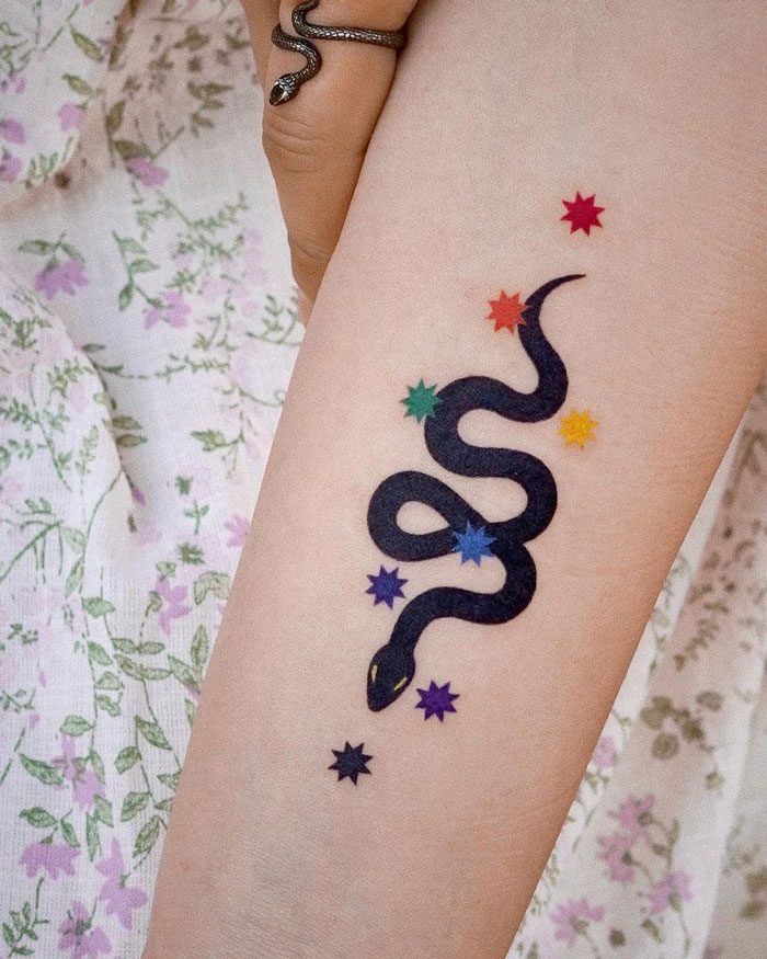Colorful snake tattoo on an arm with star accents, showcasing unique animal tattoo inspiration.
