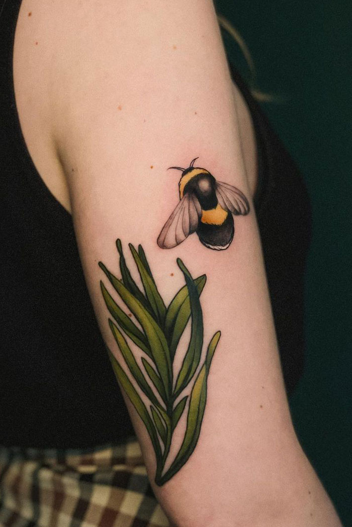 Tattoo of a bee and green leaves on a person's arm, showcasing creative animal tattoo design.