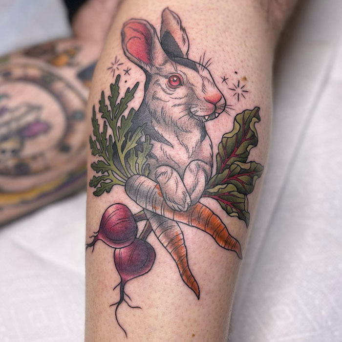 Animal tattoo featuring a rabbit with carrots and beets, showcasing colorful and detailed ink art.