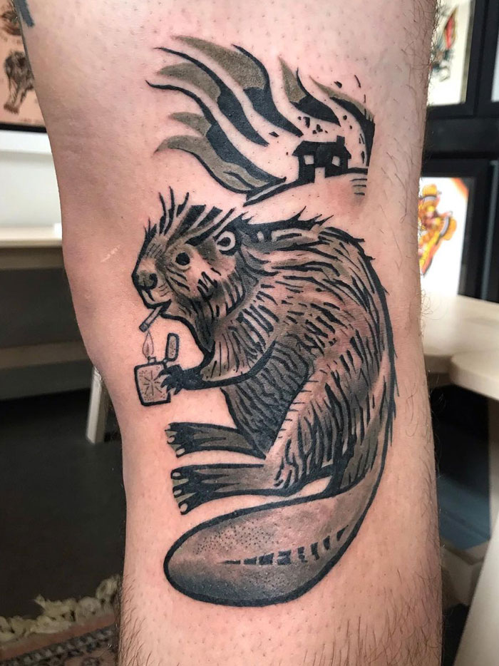 Animal tattoo of a beaver drinking from a mug by a house, with stylized smoke, on a person's leg.