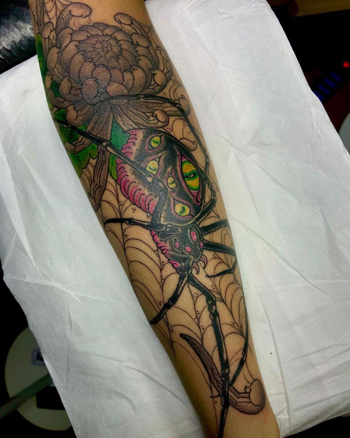 Colorful spider tattoo showcasing realism and simplicity on an arm with web details.