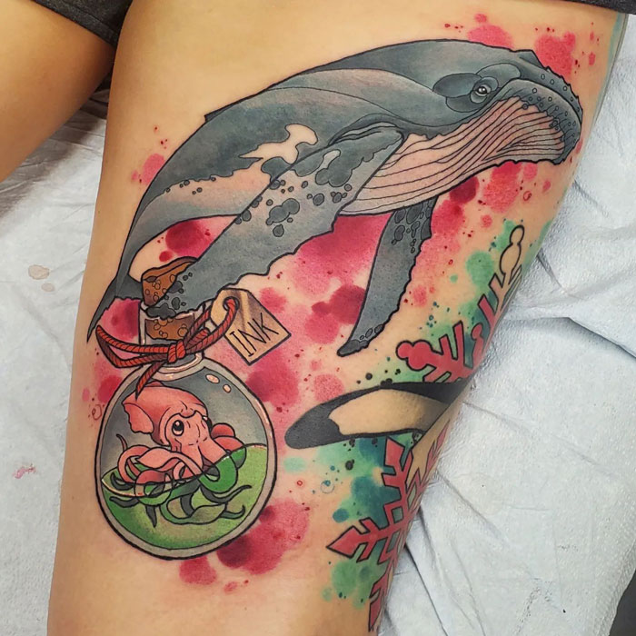 Colorful animal tattoo featuring a whale and an octopus in an ink bottle on a person's leg.