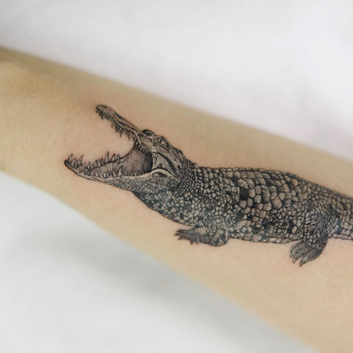 Crocodile tattoo on forearm, showcasing detailed animal artwork.