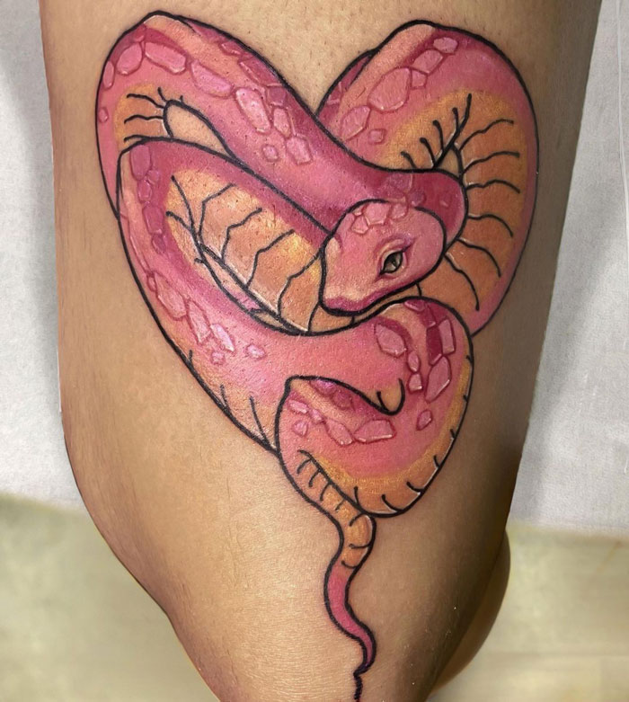 Pink snake tattoo in the shape of a heart on skin, showcasing unique animal tattoo design inspiration.
