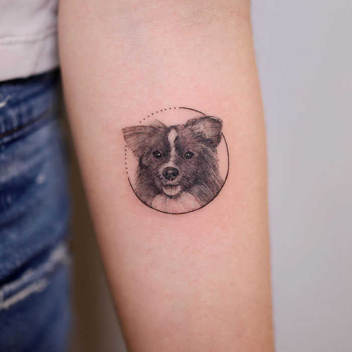 Tattoo of a dog's face inside a circle on an arm, representing the animal kingdom.