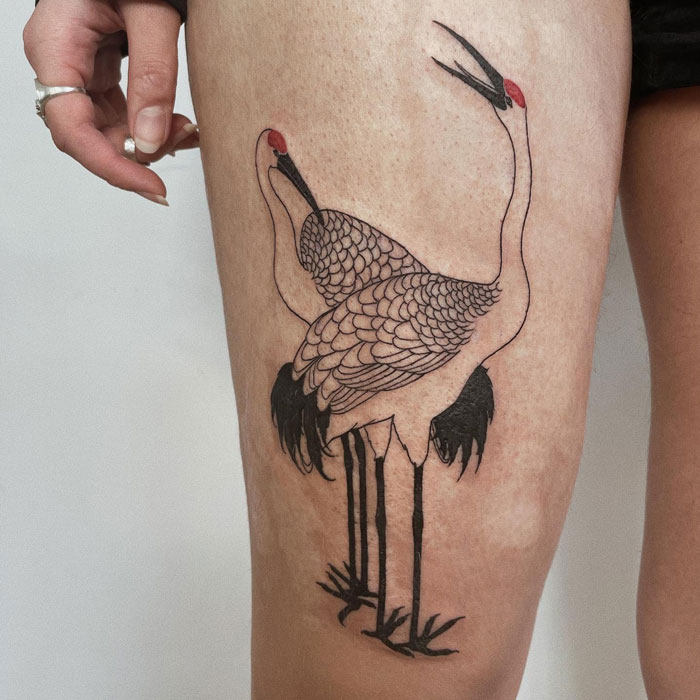 Animal tattoo of two cranes on a person's thigh, intricately detailed and creatively positioned.