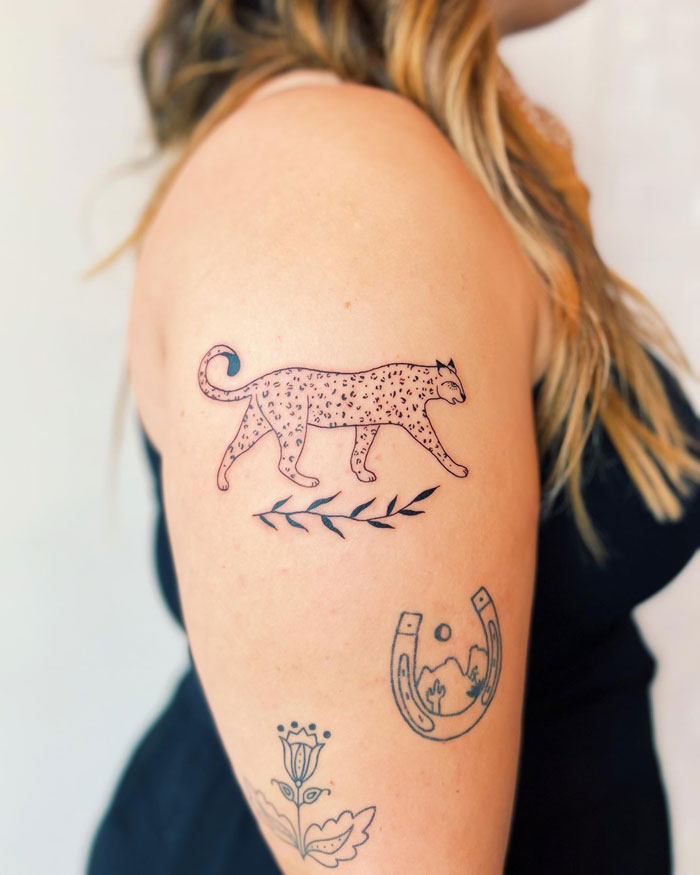 Leopard tattoo with floral designs on a woman's arm, celebrating animal kingdom artistry.
