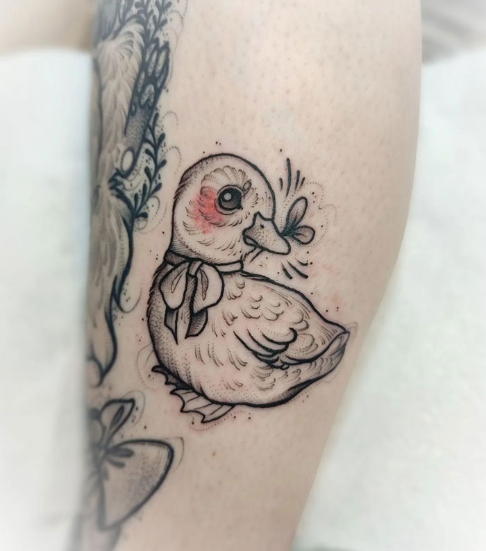 Duck tattoo on skin, showcasing animal kingdom artistry with a cute duckling and butterfly design.