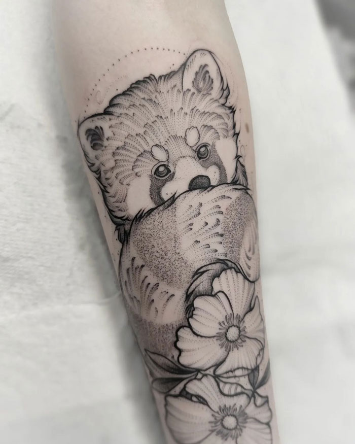 Simple and realistic red panda tattoo design with floral accents on forearm.
