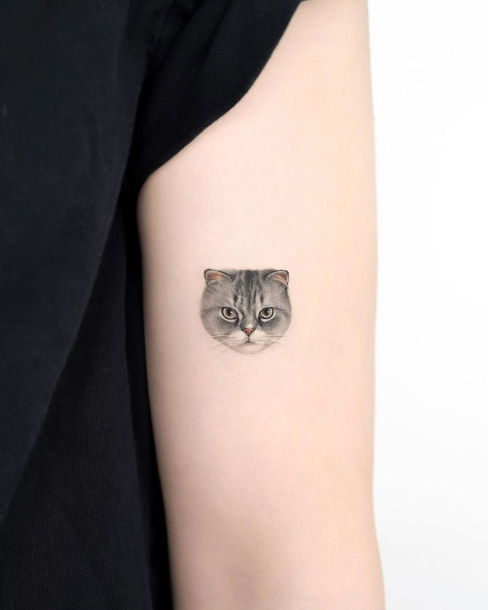 Small cat face tattoo on arm, showcasing a detailed animal design.