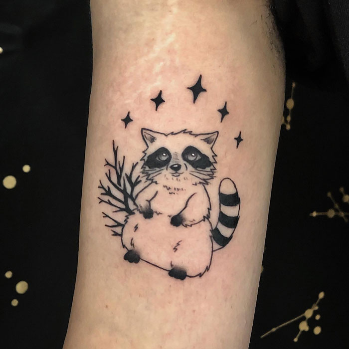 Raccoon tattoo with stars and branch, showcasing creative animal tattoo design.