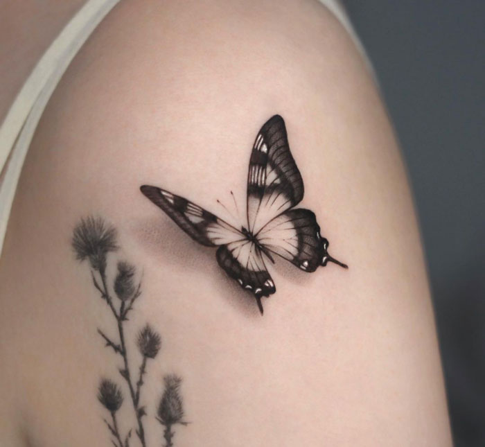 Butterfly tattoo on shoulder beside floral design, showcasing creative animal tattoo ideas.
