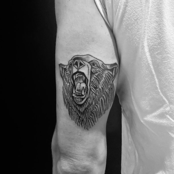 Bear tattoo on arm celebrating the animal kingdom, showcasing intricate line work and bold design.