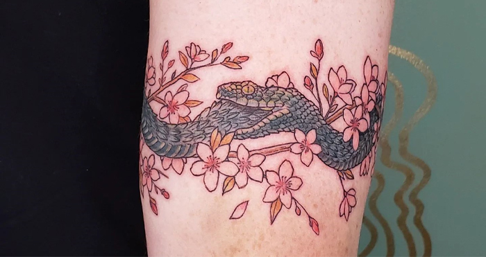 Snake and cherry blossom armband tattoo design on forearm, showcasing intricate details and artistry.