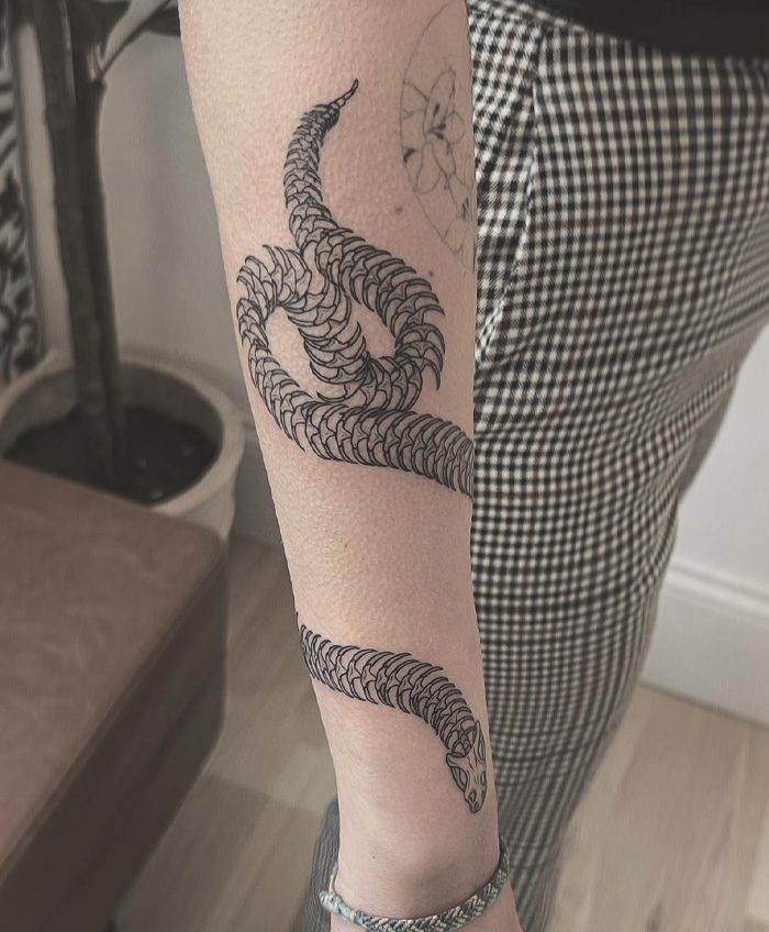 Snake design armband tattoo on forearm, showcasing intricate details and unique style.