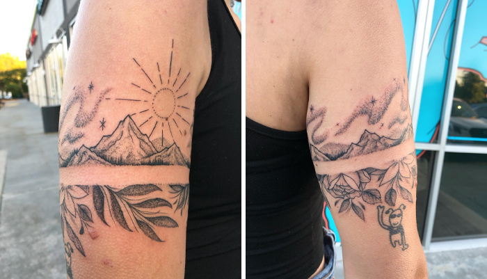 Armband tattoo featuring a landscape design with mountains, sun, and leaves on a person's arm.