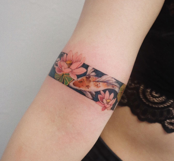 Armband tattoo featuring koi fish and lotus flowers in vivid colors.