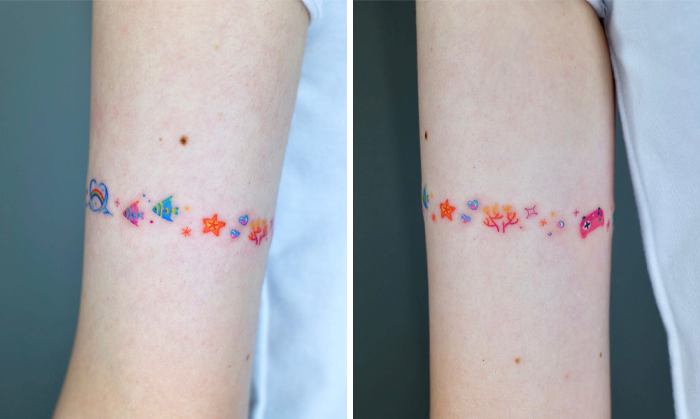 Colorful armband tattoo design featuring small symbols and stars on the upper arm.