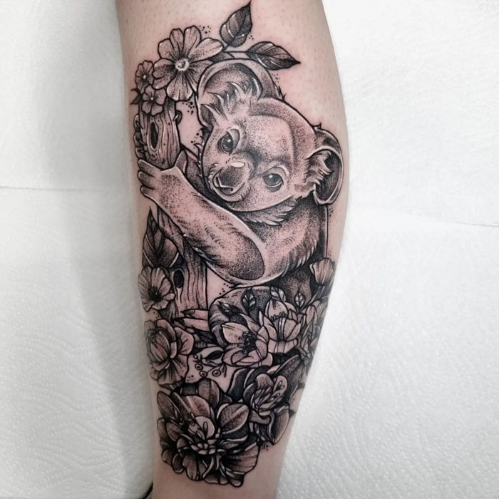 Koala calf tattoo design surrounded by detailed flowers.
