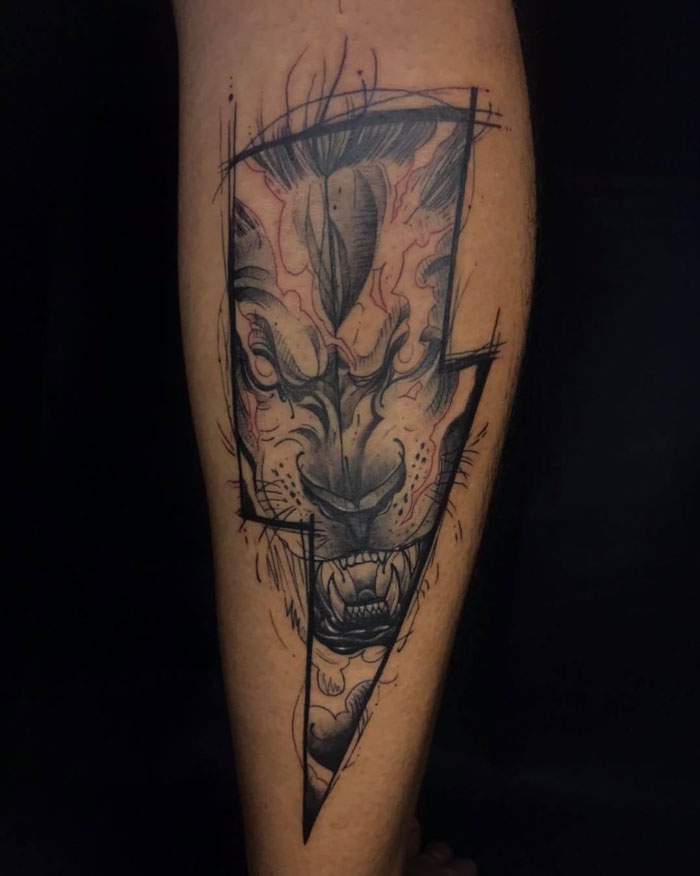 Unique calf tattoo featuring a stylized lion design with bold, artistic lines.