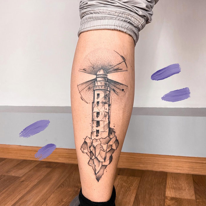 Lower leg tattoo featuring a lighthouse design with artistic elements.