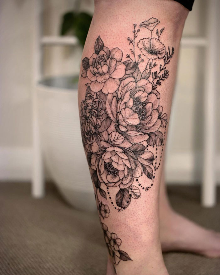 Floral calf tattoo in black ink showcasing intricate roses and leaves.