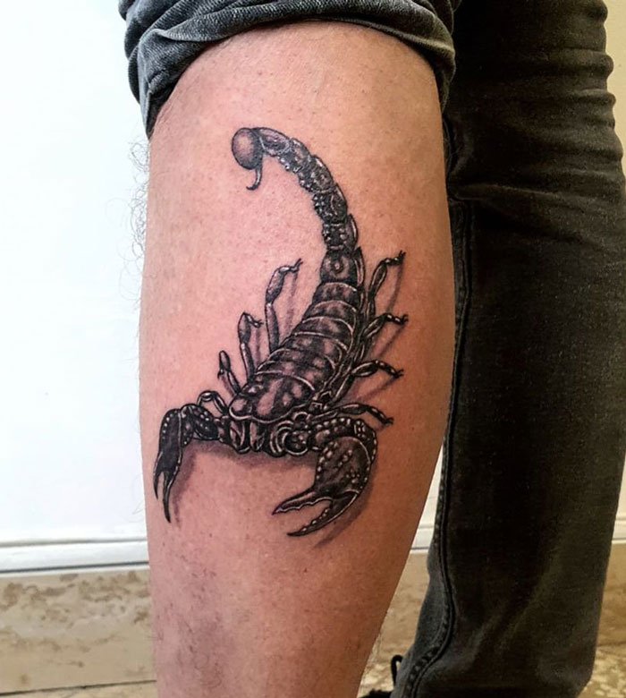 Scorpion calf tattoo displaying intricate black ink design.