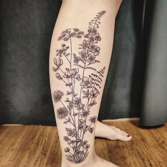 Floral calf tattoo showcasing intricate linework and botanical designs, embodying pure coolness.