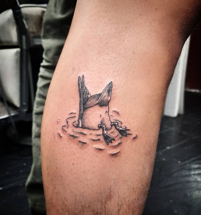 Calf tattoo of a duck diving into water, showcasing pure coolness and creativity.