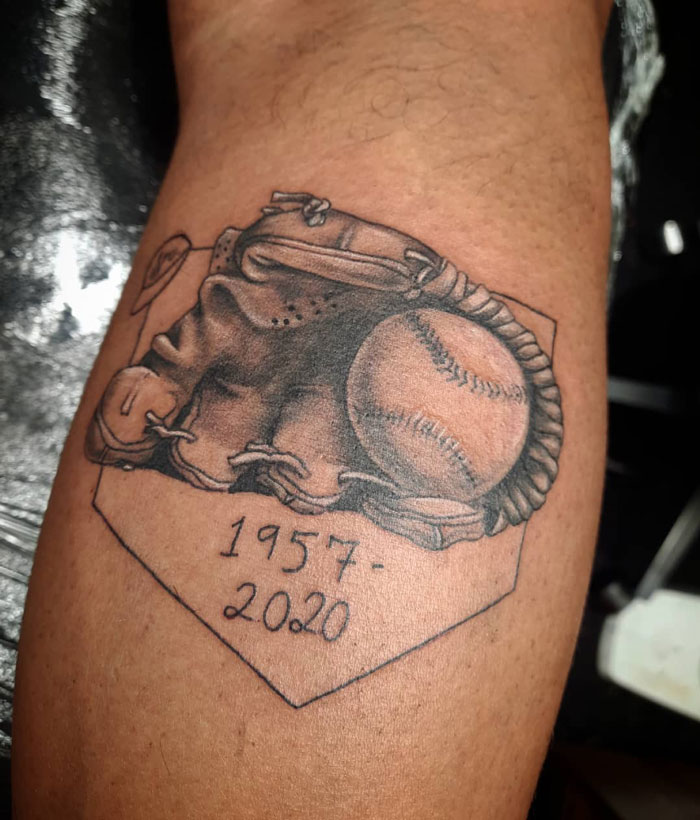 Lower leg tattoo of a detailed baseball glove and ball with the years 1957-2020.