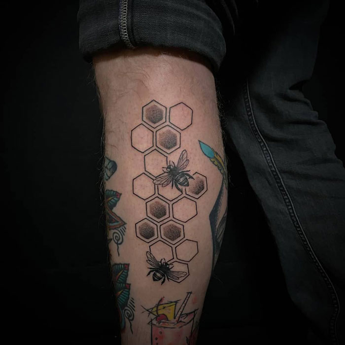 Lower leg tattoos featuring bees and honeycomb pattern on calf.