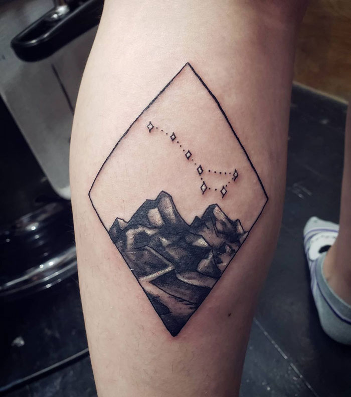 Calf tattoo featuring a geometric mountain design with stars.