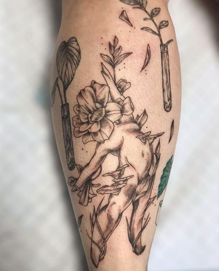 Calf tattoo featuring a cherub entwined with flowers and leaves in a unique artistic design.