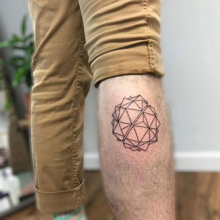 Geometric calf tattoo design, showcasing unique and cool style on a person's leg in rolled-up pants.