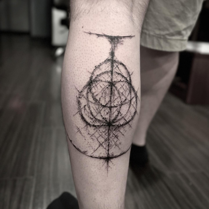 Geometric lower leg tattoo featuring abstract circular design in a minimalist style.
