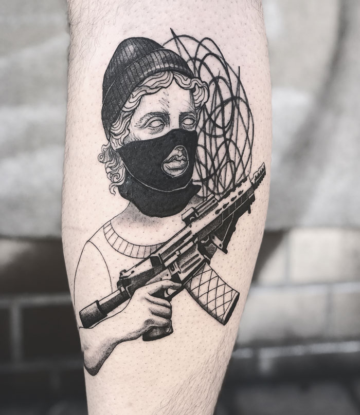 Tattoo of a masked figure with a rifle on a calf, showcasing unique calf tattoo ideas.