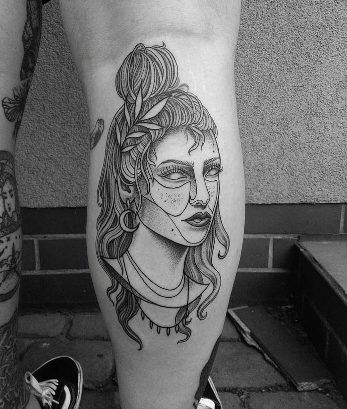 Calf tattoo depicting a woman's face with detailed line art and geometric patterns.