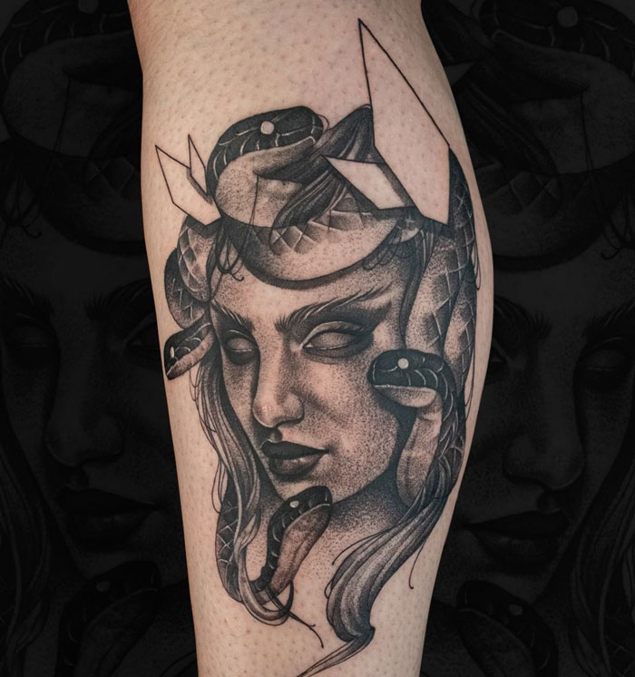 Lower leg tattoo featuring a detailed Medusa design with snakes entwined around a woman's face.