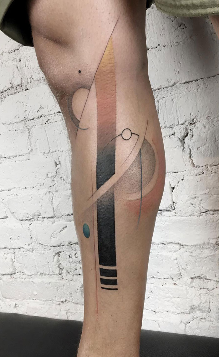 Abstract lower leg tattoo featuring geometric shapes and pastel colors.