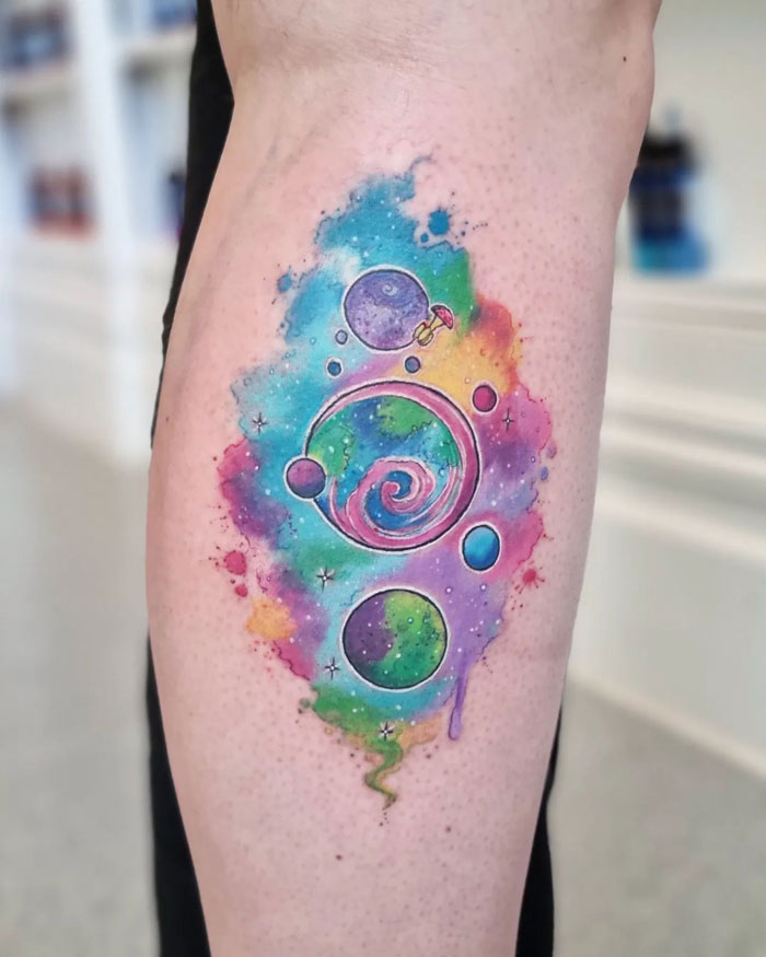 Colorful galaxy-themed lower leg tattoo with planets and swirling patterns.