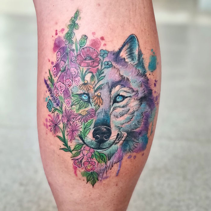 Colorful wolf and floral design on a calf tattoo displaying pure coolness.