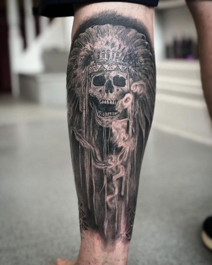 Calf tattoo featuring a detailed skull with a headdress, showcasing cool and intricate design.
