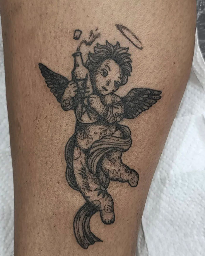 Angel-themed calf tattoo with halo and wings, showcasing intricate details and cool design.
