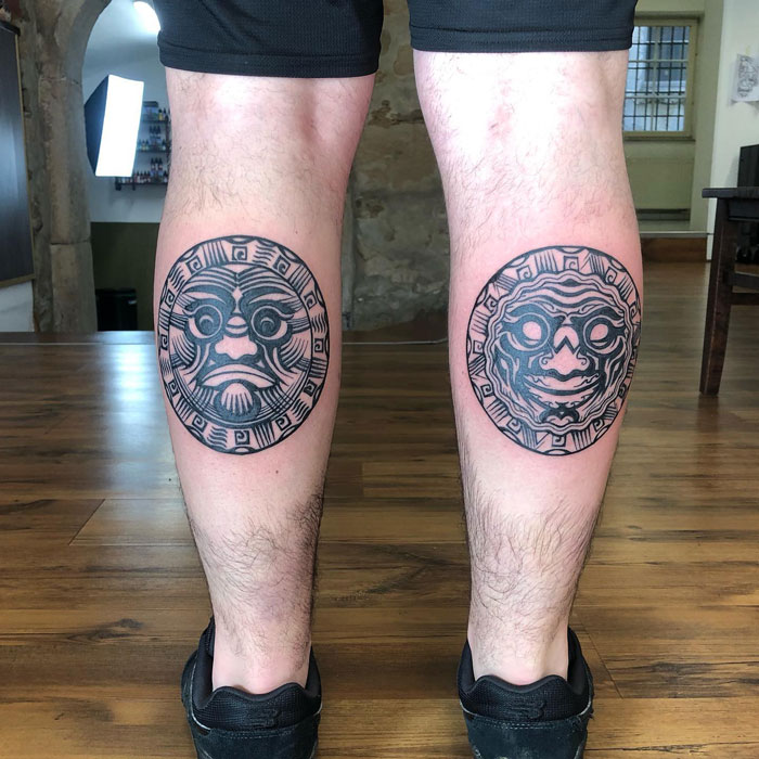 Calf tattoos featuring tribal sun and moon designs on a person's legs.