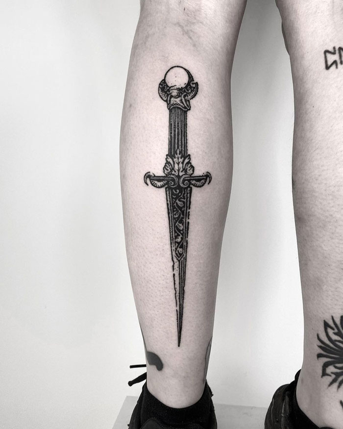 Ornate sword design tattoo on lower leg, showcasing one of the many awesome lower leg tattoos available online.