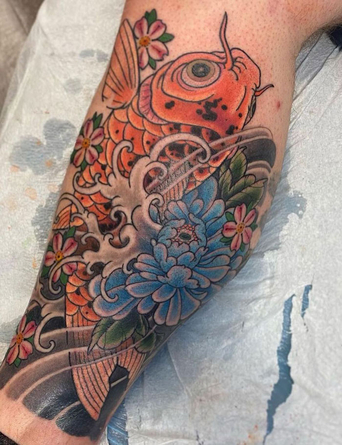 Colorful koi fish and flowers calf tattoo showcasing intricate details and coolness.