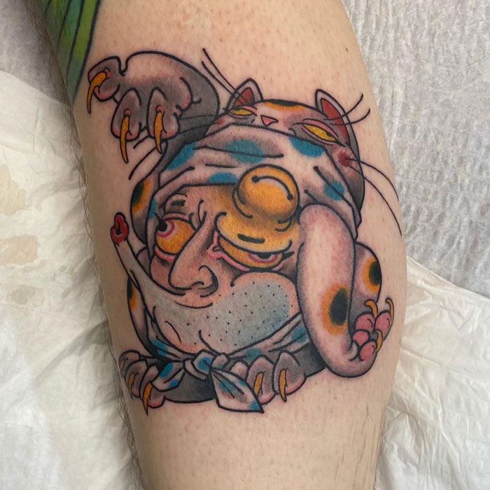 Colorful, whimsical calf tattoo featuring cartoonish character with vibrant details.