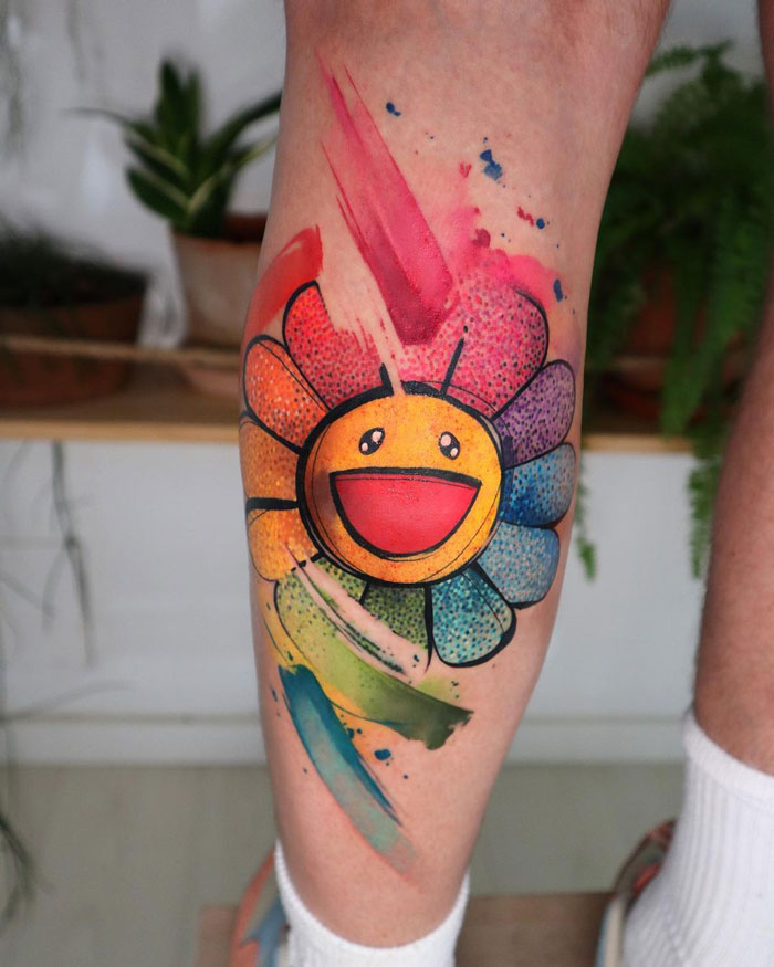Colorful smiley flower calf tattoo, showcasing vibrant ink art.